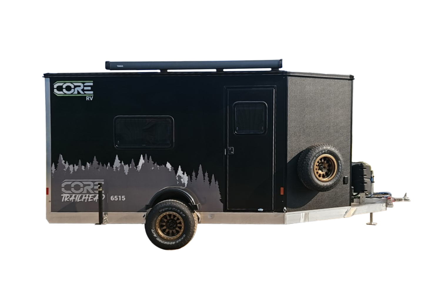 Exterior curbside view of the CORE RV 6515 Trailhead trailer, black with grey trees graphics and an awning mounted on top